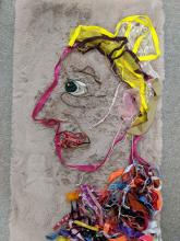 A self portrait of myself, Sarah Olive Edwards, made using a pink cuddly blanket and lots of colourful ribbons outlinging a face a shoulders.
